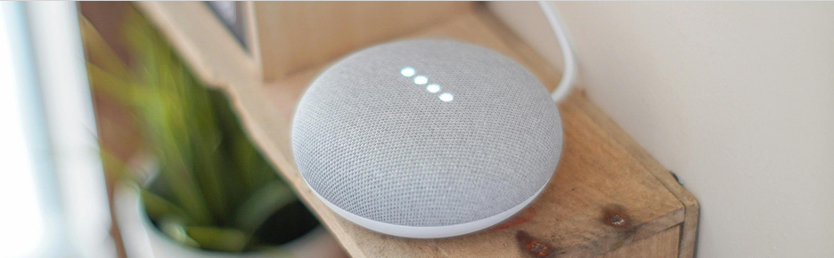 Smart home assistant speaker on a wooden shelf.