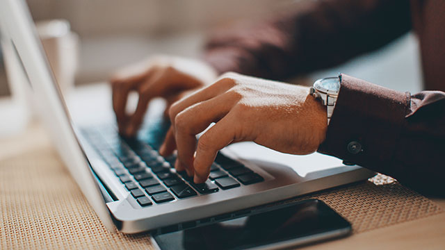 Person typing on a laptop on a desk.