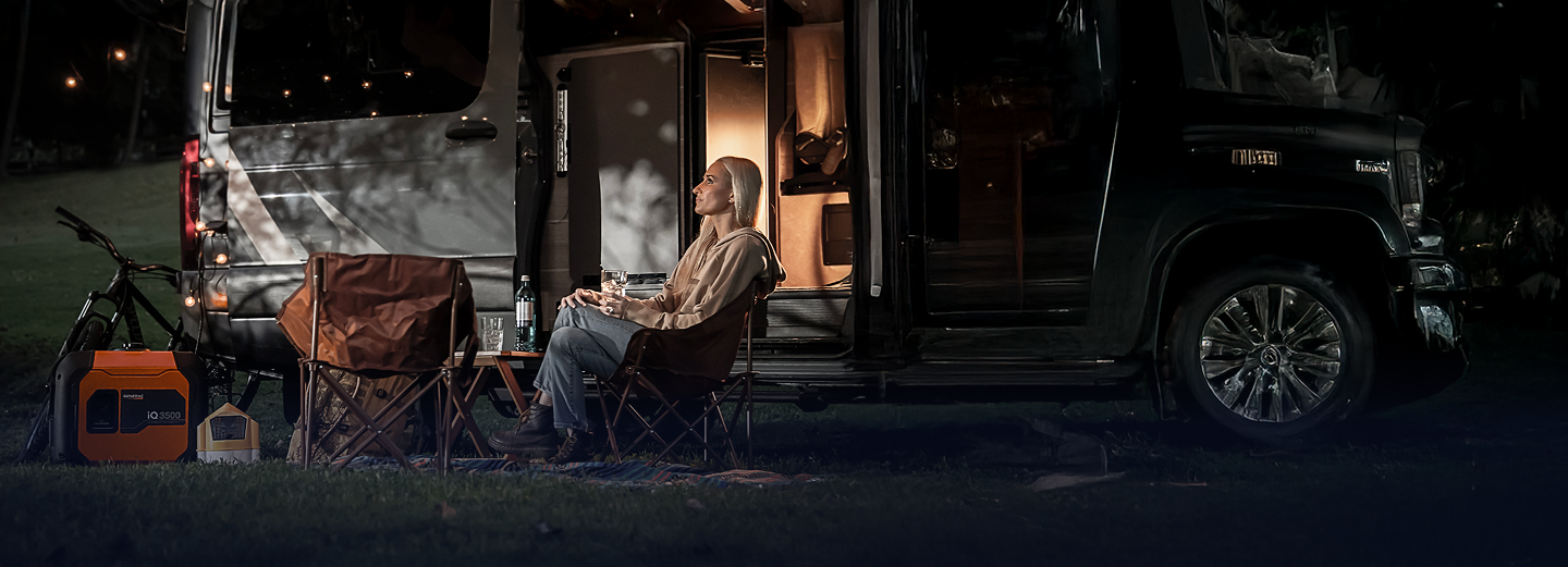 Woman sitting outside RV with portable generators at night